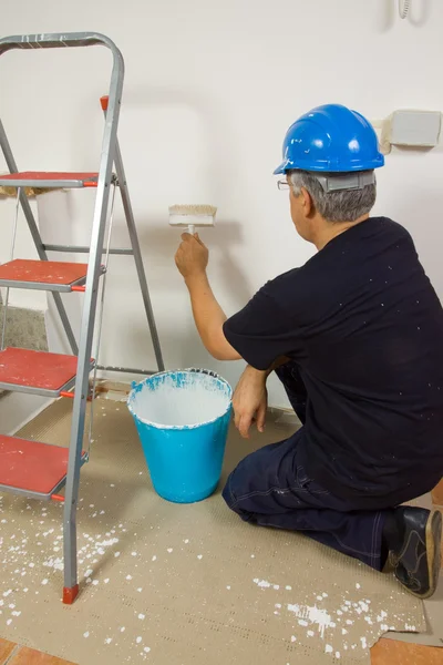 Travailleur peint le mur avec une brosse — Photo