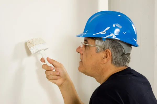 Travailleur peint le mur avec une brosse — Photo