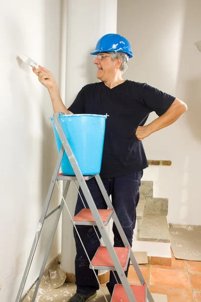 Trabajador pinta la pared con un pincel — Foto de Stock