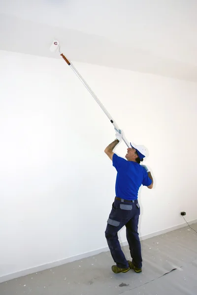 Trabajador pinta el techo con un rodillo de anclaje —  Fotos de Stock