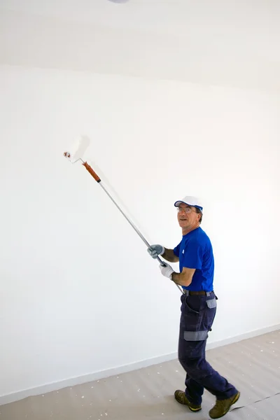 Worker pinta la pared con un rodillo de anclaje — Foto de Stock