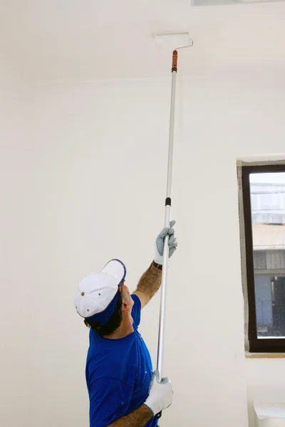 Trabajador pinta el techo con un rodillo de anclaje —  Fotos de Stock