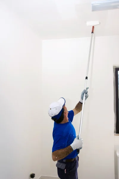 Travailleur peint le plafond avec un rouleau d'ancrage — Photo
