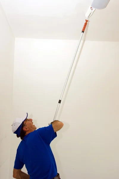 Pracownik maluje sufit z winda kotwiczna — Zdjęcie stockowe