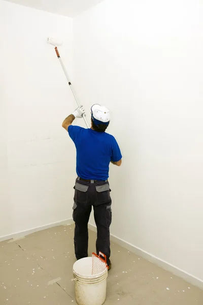 Εργαζόμενος ζωγραφίζει τον τοίχο με μια άγκυρα κυλίνδρου — Φωτογραφία Αρχείου