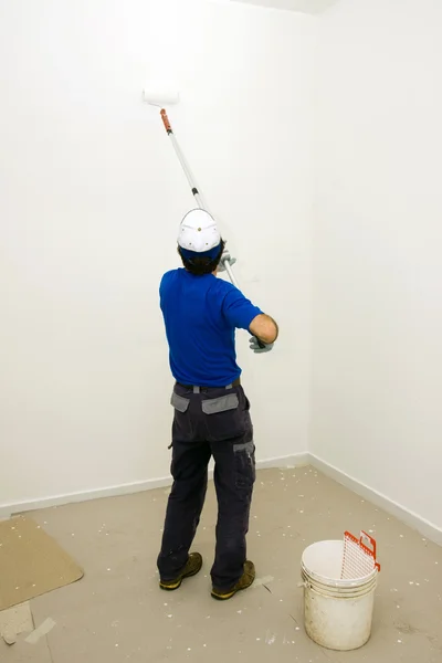 Worker pinta la pared con un rodillo de anclaje — Foto de Stock