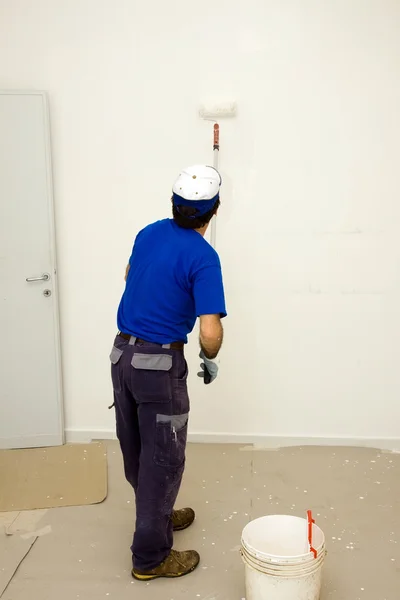 Worker pinta la pared con un rodillo de anclaje — Foto de Stock