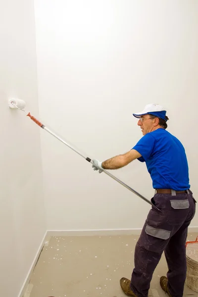 Worker pinta la pared con un rodillo de anclaje — Foto de Stock