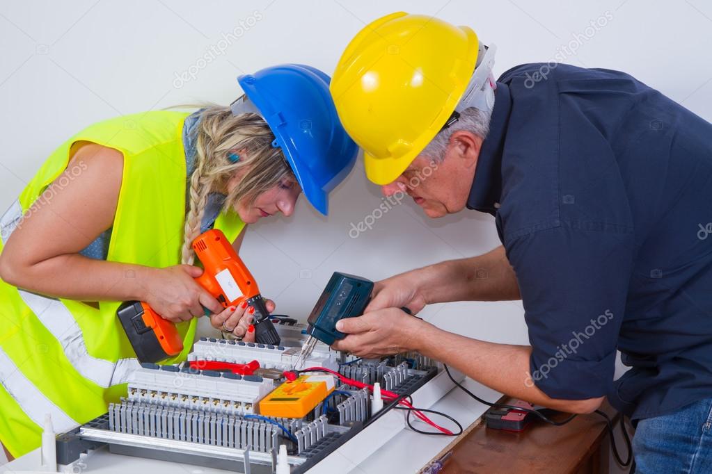 Electricians working indoors on electrical tasks.