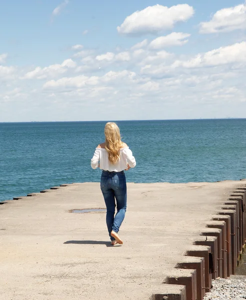 桟橋の上を歩く若いブロンドの女性. — ストック写真