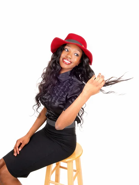 Black woman with red hat sitting on chair. — Stock Photo, Image