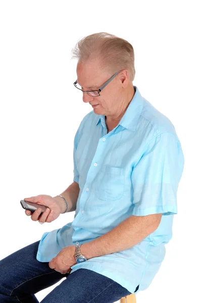 Oudere man kijken naar zijn mobiele telefoon. — Stockfoto