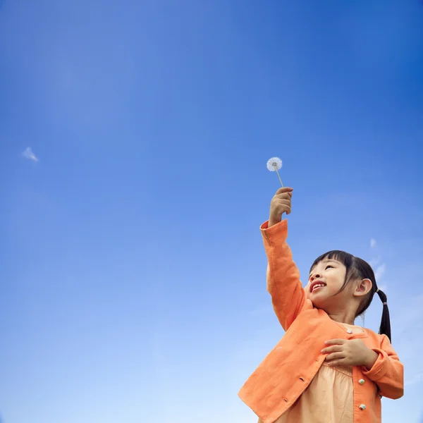 Girl with is holding dandelion in hand while standing — Stock Photo, Image