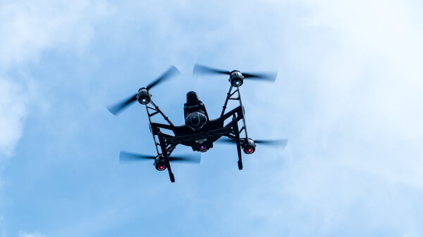 Коптер с камерой, летящий по ясному солнечному небу
