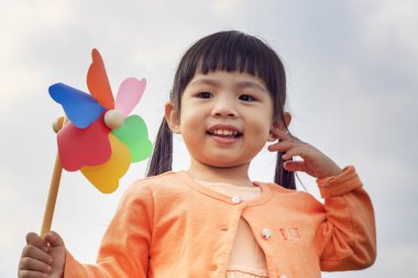 sevimli küçük kız yaz günü çim üzerinde tutan yel değirmeni