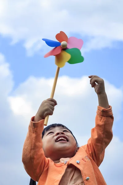 Cute little girl on grass in summer day holds windmill — Stock Photo, Image