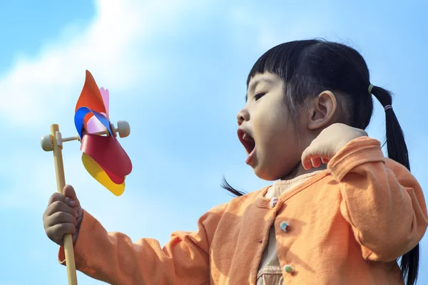 Cute little girl on grass in summer day holds windmill — Stock Photo, Image