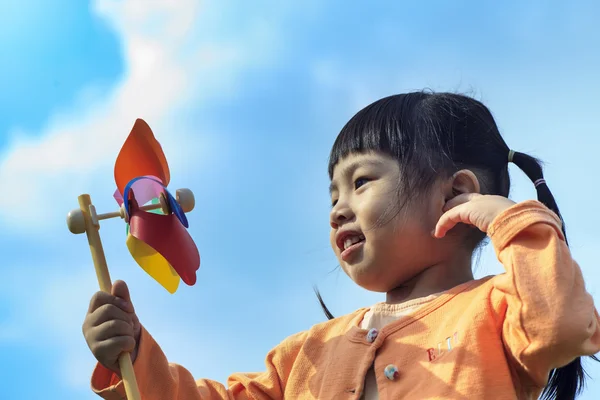 Cute little girl on grass in summer day holds windmill — Stock Photo, Image