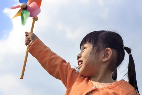 Cute little girl on grass in summer day holds windmill — Stock Photo, Image