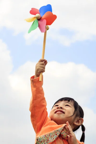 Słodkie dziewczynki na trawie w letni dzień posiada wiatrak — Zdjęcie stockowe