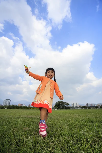 Sevimli küçük kız yaz günü çim üzerinde tutan yel değirmeni — Stok fotoğraf