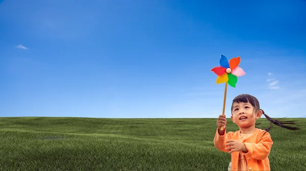 Fechar-se de menina soprando roda de vento — Fotografia de Stock