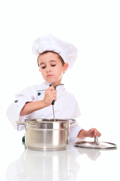 Kleine jongen chef-kok met pollepel stiring in de pot Stockfoto