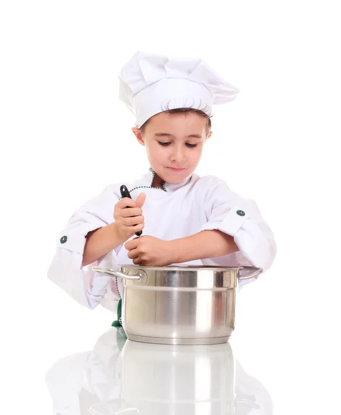小男孩厨师与钢包在锅里搅拌 免版税图库照片