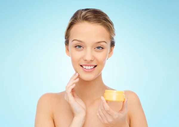 Happy young woman applying cream to her face — Stock Photo, Image