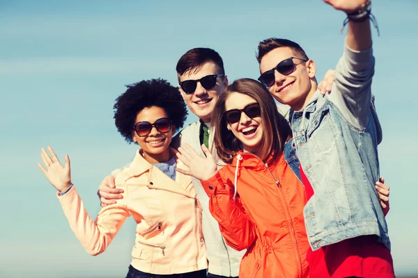 Happy tonåriga vänner i nyanser viftande händer — Stockfoto