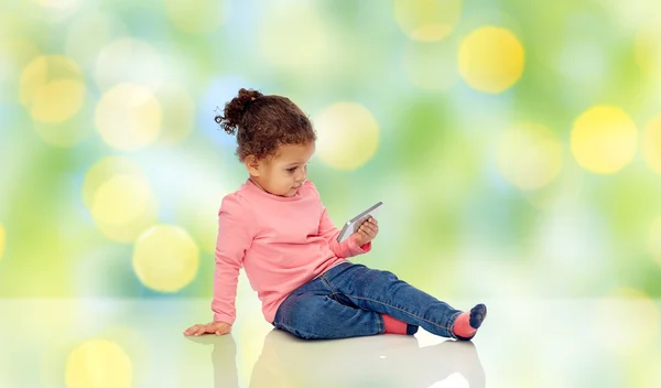 Lächelndes kleines Mädchen spielt mit Smartphone — Stockfoto