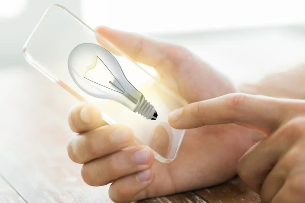 Close up of hand with light bulb on smartphone — Stock Photo, Image