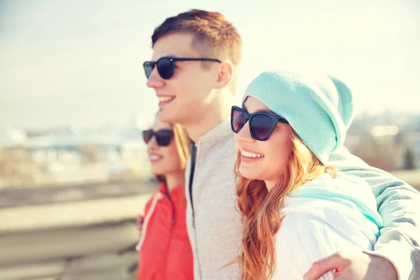 Happy teenage friends in shades hugging on street — Stock Photo, Image