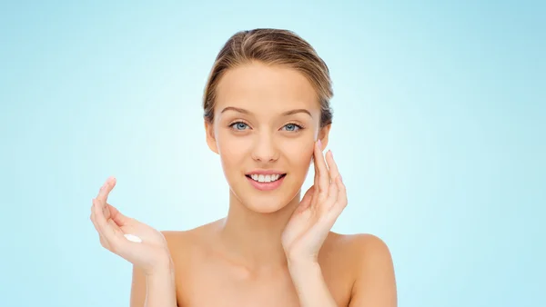 Gelukkig jonge vrouw crème op haar gezicht toe te passen — Stockfoto