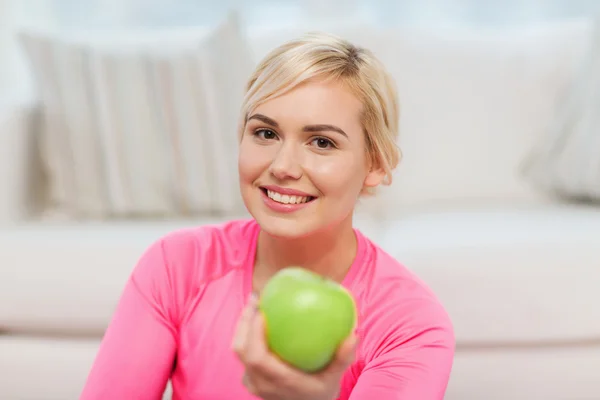 Glückliche Frau isst grünen Apfel zu Hause — Stockfoto