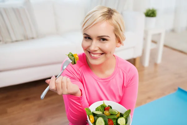 Gülümseyen genç kadın evde salata yemek — Stok fotoğraf