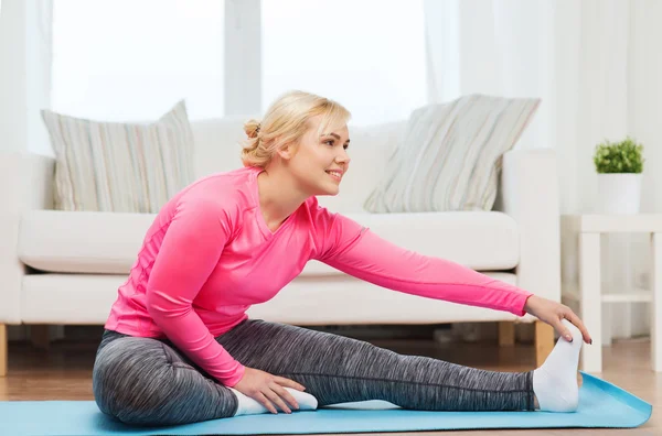 Femme heureuse étirant jambe sur tapis à la maison — Photo