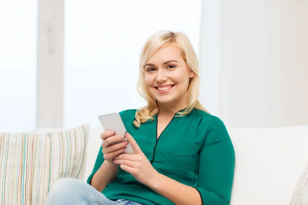 Счастливая женщина со смартфоном дома — стоковое фото