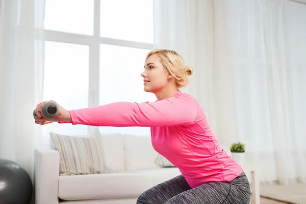 Mujer sonriente con mancuernas haciendo ejercicio en casa —  Fotos de Stock
