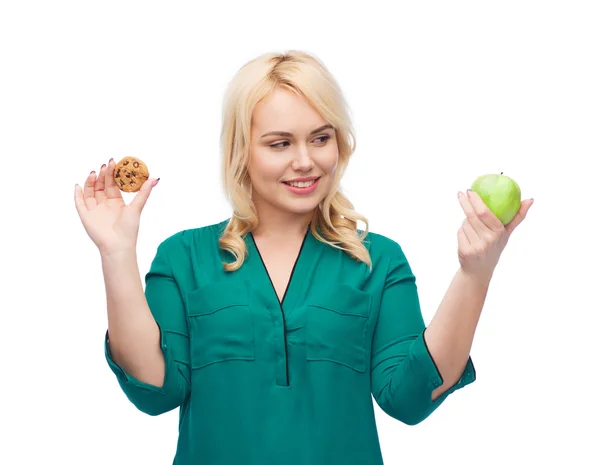 Femme souriante choisir entre pomme et biscuit — Photo