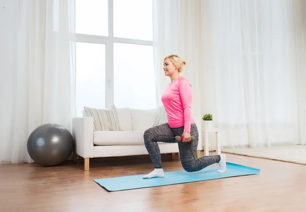 Smiling woman with dumbbells exercising at home — Stock Photo, Image