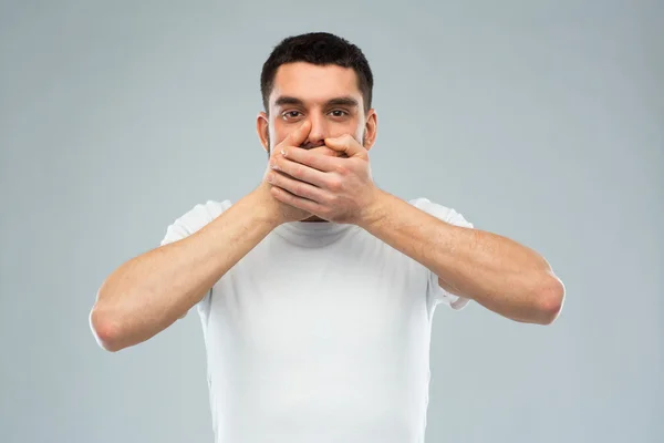 Man in white t-shirt covering his mouth with hands — Stock Photo, Image