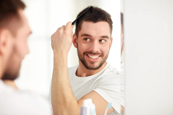 Gelukkig man borstelen van haar met kam op badkamer — Stockfoto