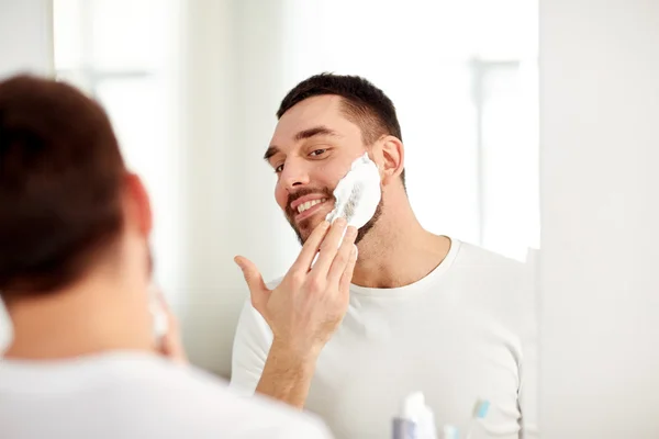 Gelukkig man scheerschuim op badkamerspiegel toe te passen — Stockfoto