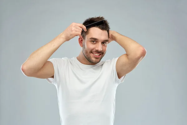 Счастливый мужчина причесывает волосы с расческой над головой — стоковое фото
