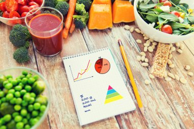 close up of ripe vegetables and notebook on table clipart