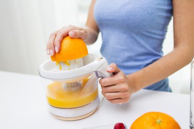 close up of woman squeezing orange juice at home clipart