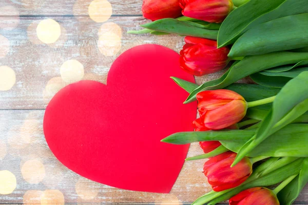 Primer plano de tulipanes rojos y tarjeta de forma de corazón de papel — Foto de Stock