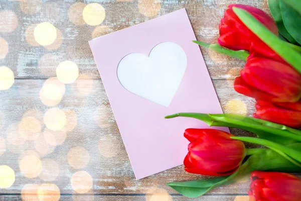 Close up of tulips and greeting card with heart — Stock Photo, Image