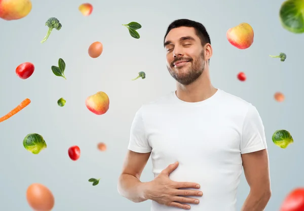 Homem cheio feliz tocando barriga sobre frutos caindo — Fotografia de Stock
